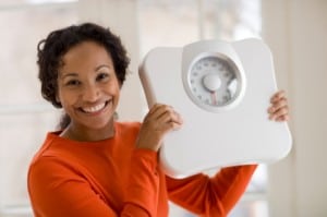 Happy Black woman holding scale
