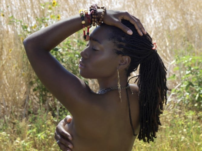 Bare back black woman outdoors covering breast