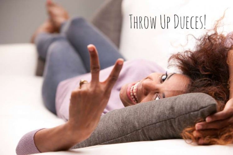 beautiful curly african-american woman lying on a sofa and showing off the winner symbol with her fingers