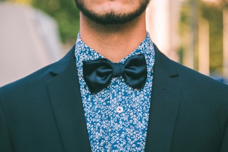 Detail of a young handsome man wearing a bow tie and posing in the city streets