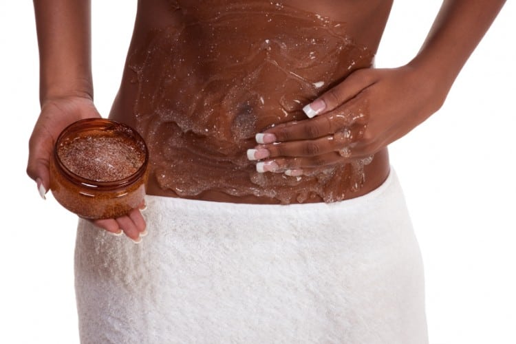 Woman skincare and bodycare procedure - topless ethnic black female body with hand applying moisturizing gel or scrubbing product on abdomen belly area.