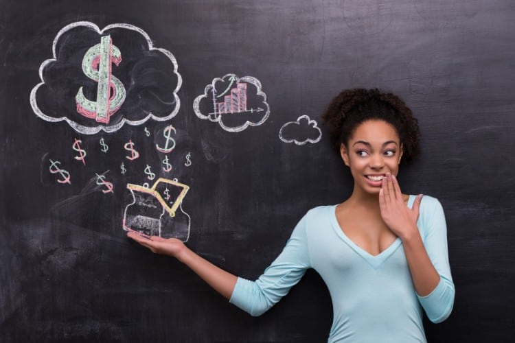Photo of young afro-american woman on chalkboard background. Woman smiling and cheerfully looking at dollar signs and purse painted on chalkboard