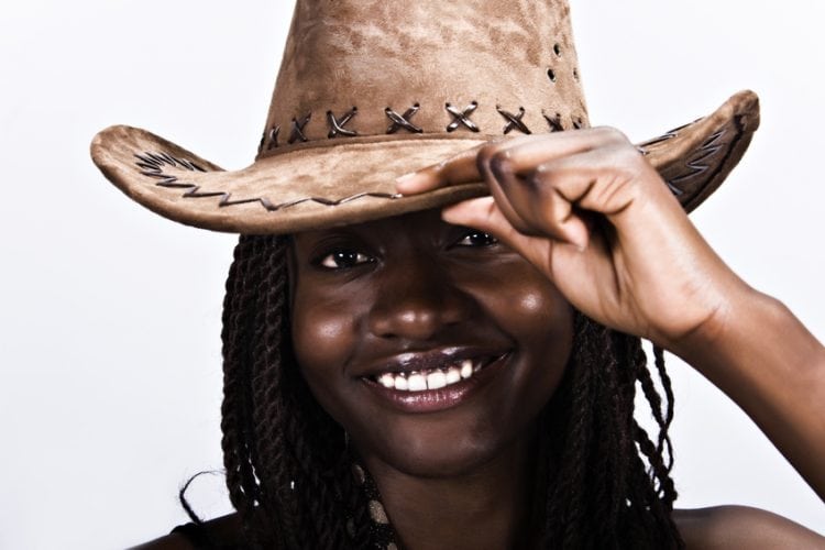 Young African woman smiling, with cowboy hat and dreadlocks hairstyle