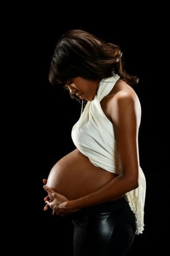 Young Black Woman Pregnant on a dark background