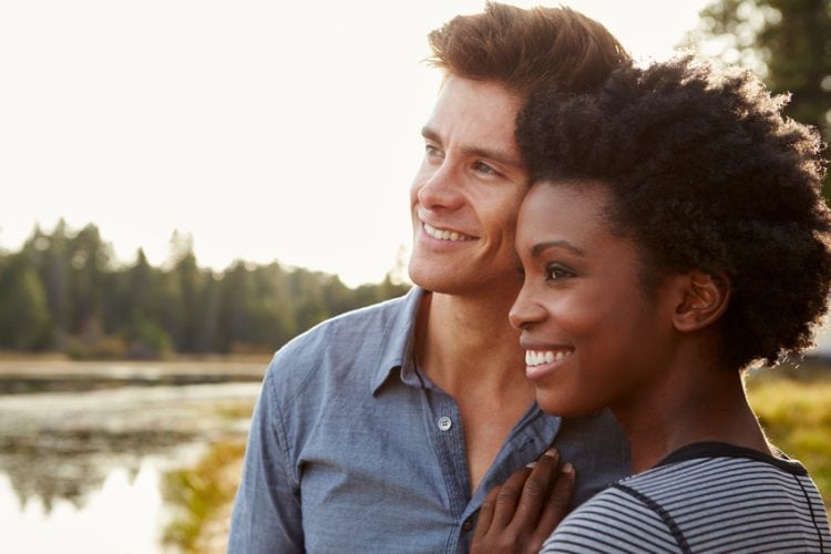 Happy mixed race couple admiring a view in the countryside