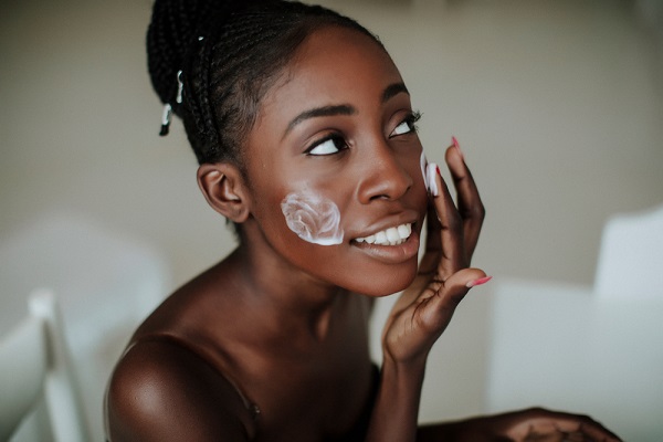 younger woman applying facial essence