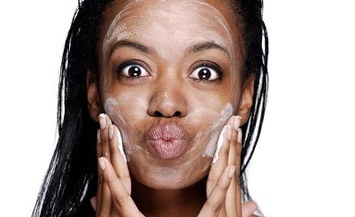 happy black woman applying facial essence