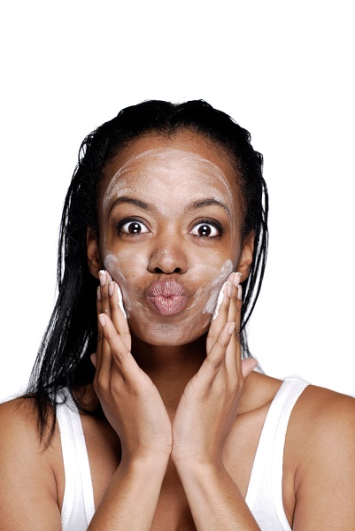 happy black woman applying facial essence